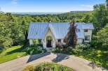 Nestled amidst lush greenery, this stunning property offers breathtaking panoramic views of the distant water and rolling hills.
