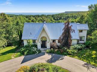Nestled amidst lush greenery, this stunning property offers breathtaking panoramic views of the distant water and rolling hills.