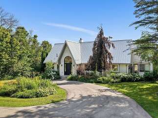 Discover this stunning home featuring a unique architectural design with a striking metal roof and an arched entryway.