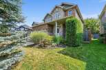 This charming two-story home features a beautiful stone and brick facade, complemented by lush landscaping and a welcoming covered porch.