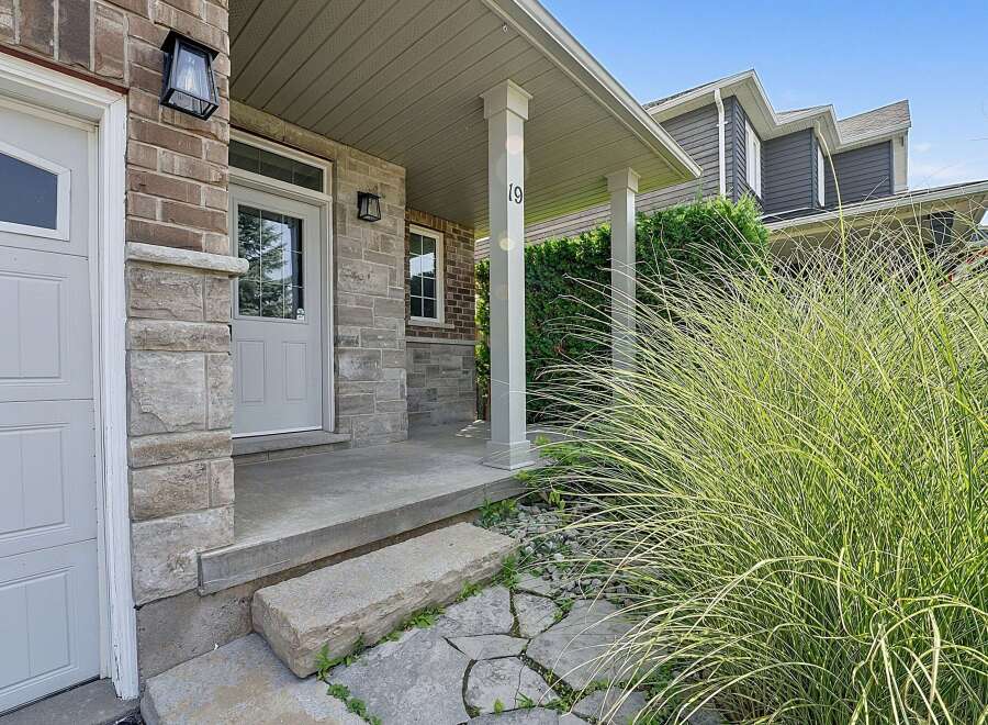 Welcome to this charming home featuring a welcoming covered porch with a classic lantern light and a prominent house number '19'.