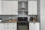 This modern kitchen features sleek white cabinetry and a stylish grey subway tile backsplash.