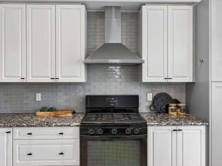 This modern kitchen features sleek white cabinetry and a stylish grey subway tile backsplash.