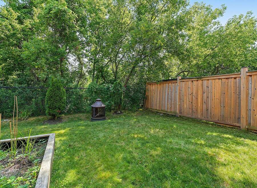 Enjoy outdoor living in this charming backyard, complete with a lush green lawn and a rustic fire pit perfect for cozy evenings.