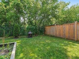 Enjoy outdoor living in this charming backyard, complete with a lush green lawn and a rustic fire pit perfect for cozy evenings.