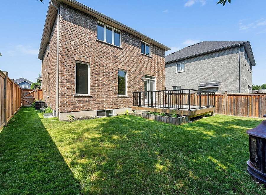 Enjoy outdoor living in this spacious backyard featuring a wooden deck perfect for entertaining and a lush green lawn.