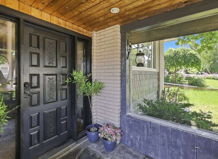 Step into this charming home through a striking black door, complemented by a warm wooden ceiling and a welcoming porch.