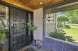 Step into this charming home through a striking black door, complemented by a warm wooden ceiling and a welcoming porch.
