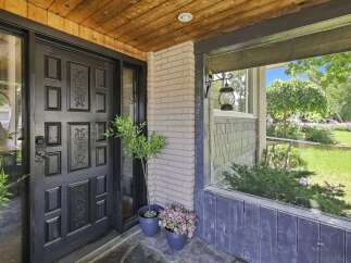 Step into this charming home through a striking black door, complemented by a warm wooden ceiling and a welcoming porch.