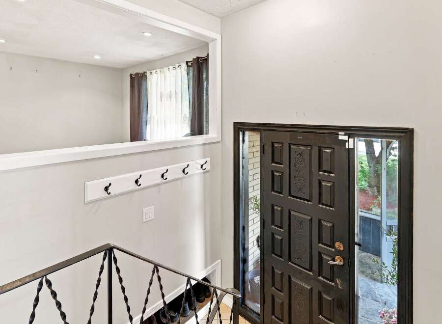 Step into this welcoming entryway featuring a dark wood paneled front door with intricate detailing and a glass insert for natural light.