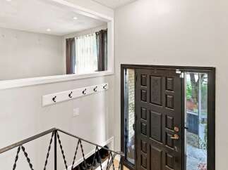 Step into this welcoming entryway featuring a dark wood paneled front door with intricate detailing and a glass insert for natural light.