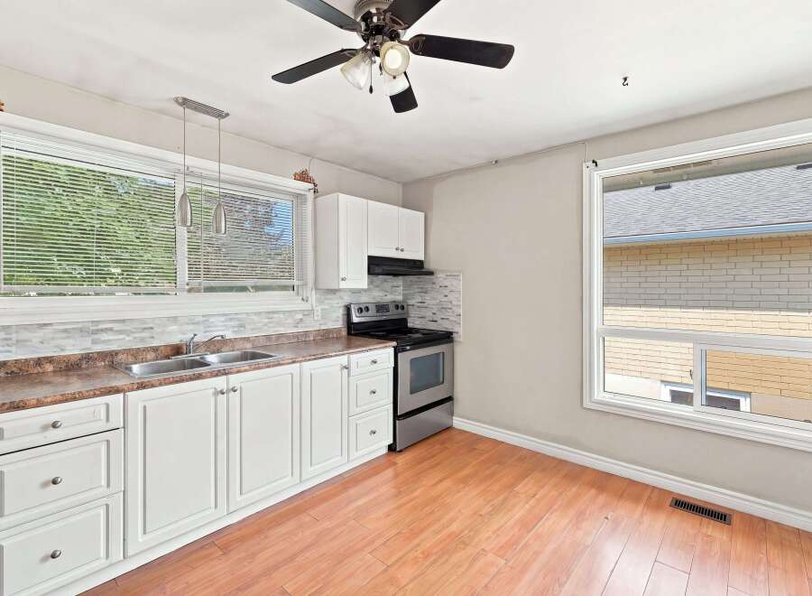 Bright and functional kitchen featuring white cabinetry, a double sink, and a stainless steel gas range.