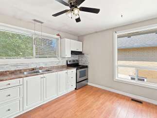 Bright and functional kitchen featuring white cabinetry, a double sink, and a stainless steel gas range.