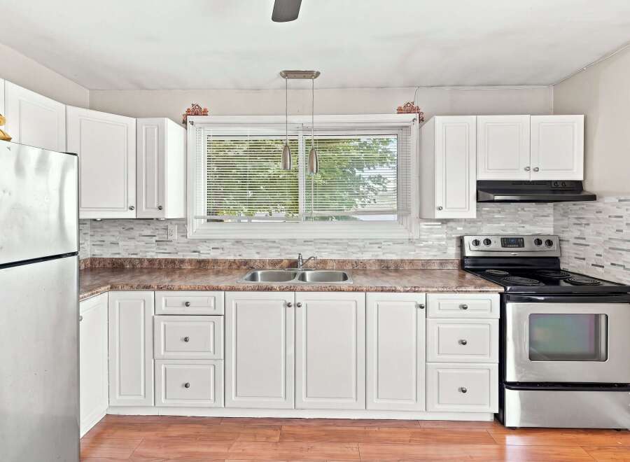 This bright and airy kitchen features clean white cabinetry and a modern backsplash, creating a sleek and functional space.