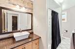 This bathroom features a stylish vessel sink atop a dark speckled countertop and light wood vanity.