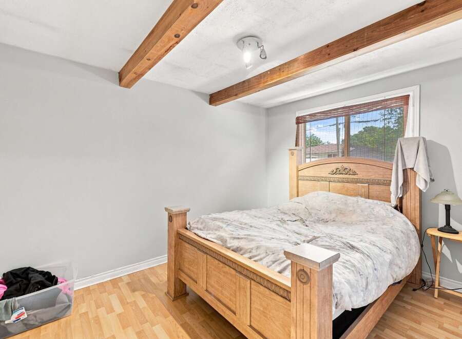 This charming bedroom features a sturdy wooden bed frame with an ornate headboard, perfect for creating a cozy retreat.