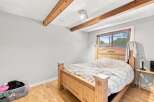 This charming bedroom features a sturdy wooden bed frame with an ornate headboard, perfect for creating a cozy retreat.
