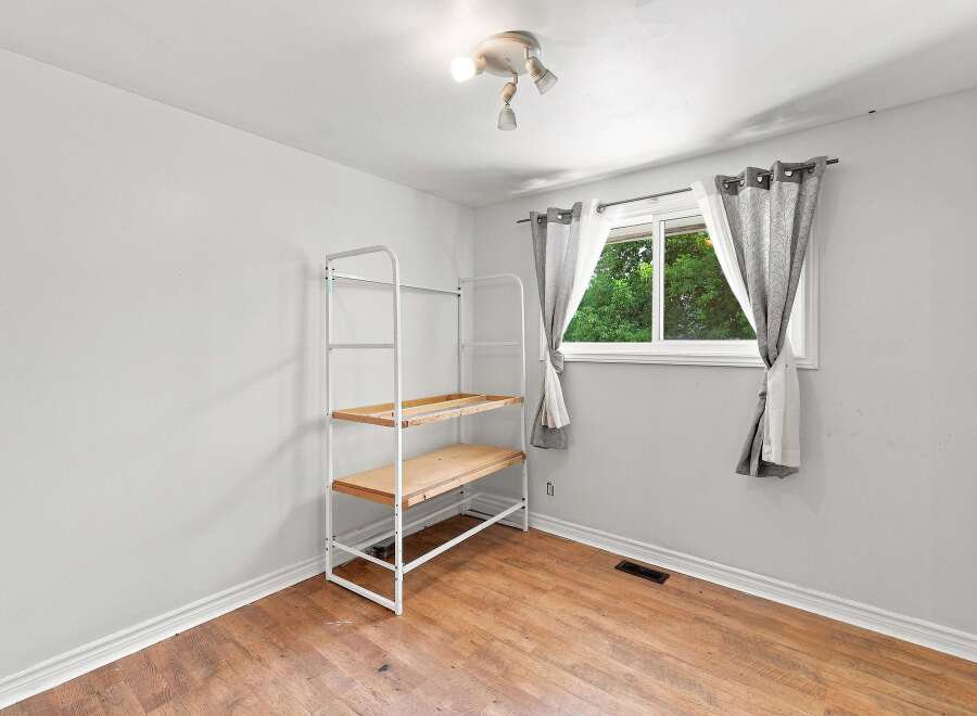 This bright and airy room features a large window with natural light flooding in, complemented by neutral gray curtains.