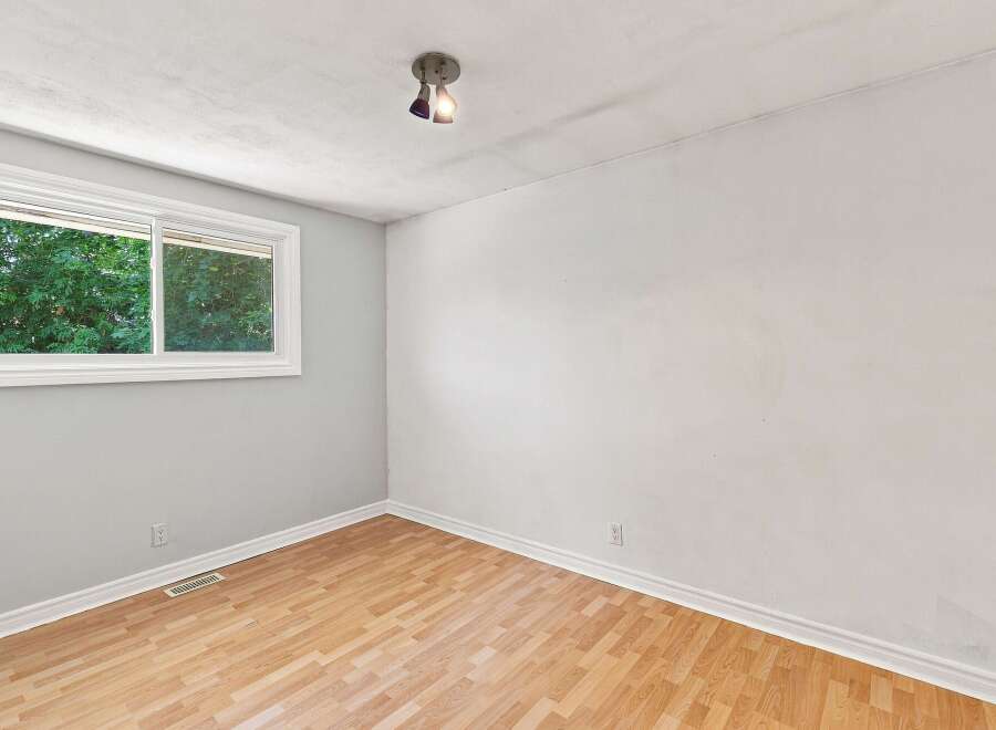 This bright and airy room features a large window offering a view of lush greenery, perfect for natural light.