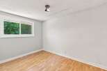 This bright and airy room features a large window offering a view of lush greenery, perfect for natural light.