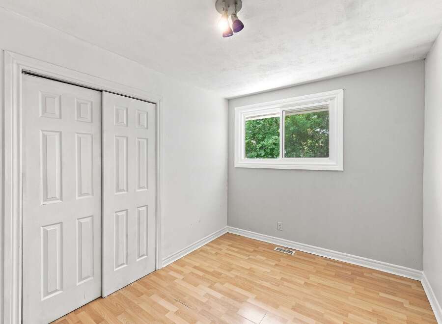 Discover comfort and style in this inviting bedroom, featuring a spacious closet with double doors and a large window that floods the room with natural light.
