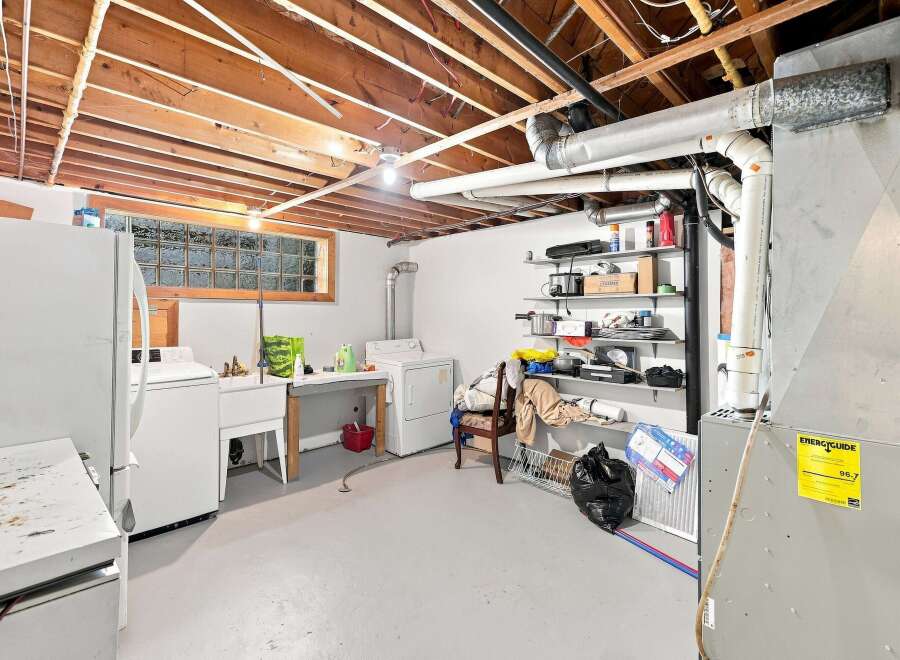 Discover the potential in this spacious basement laundry room, featuring a large utility sink, washer, and dryer.