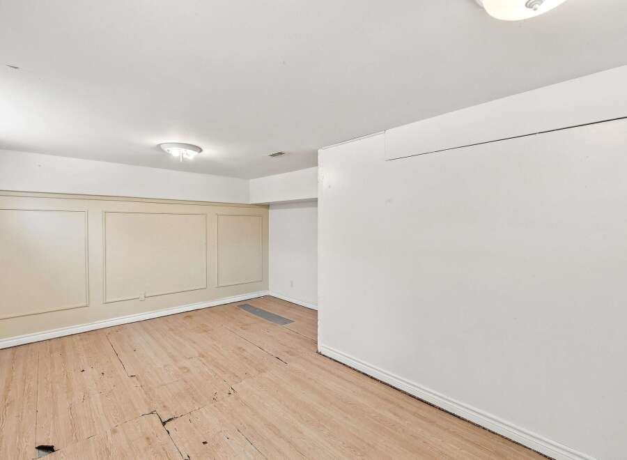 This spacious room features a neutral color palette with elegant wainscoting on the walls, offering a classic and versatile backdrop.