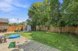 Enjoy outdoor living in this spacious backyard featuring a wooden deck, a blue kiddie pool, and a well-maintained lawn perfect for recreation.