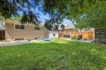Enjoy outdoor living in this spacious backyard, complete with a lush green lawn perfect for recreation.