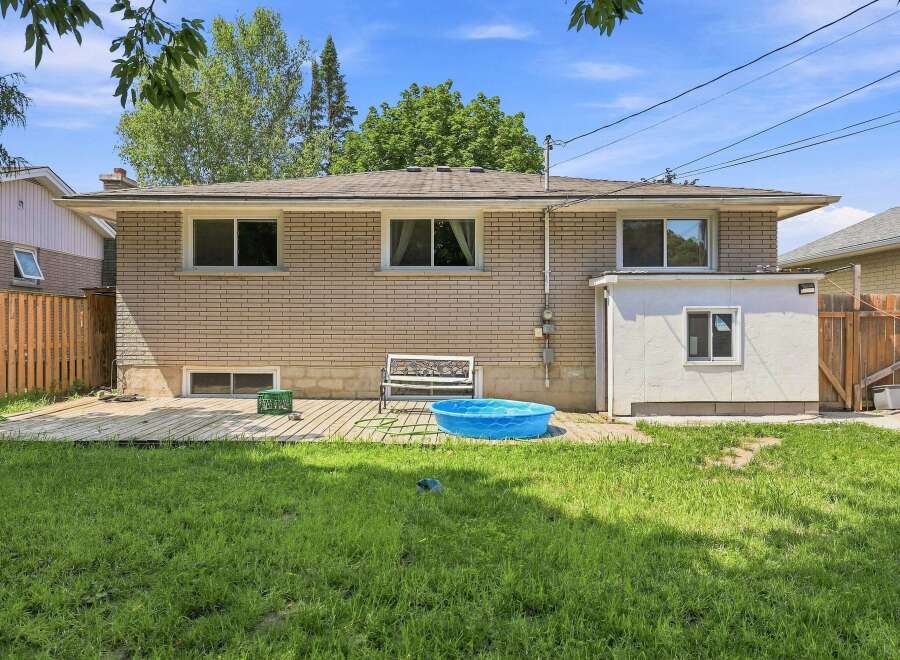 Enjoy outdoor living with this spacious backyard featuring a wooden deck perfect for entertaining and a refreshing blue kiddie pool for summer fun.