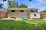 Enjoy outdoor living with this spacious backyard featuring a wooden deck perfect for entertaining and a refreshing blue kiddie pool for summer fun.