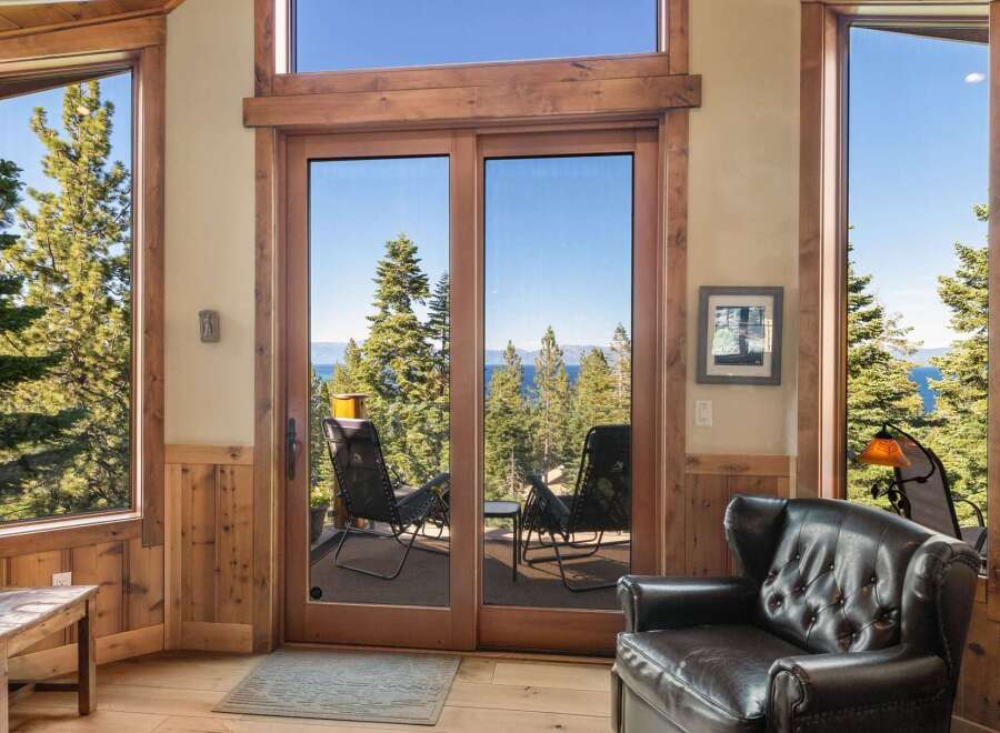 Experience breathtaking lake and mountain views from this stunning living space, featuring expansive windows and sliding glass doors that seamlessly blend indoor and outdoor living.
