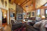 Experience rustic elegance in this stunning living room, featuring a grand stone fireplace and a vaulted wood-paneled ceiling.