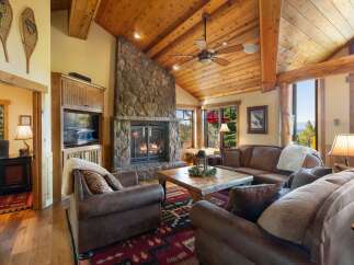 Experience rustic elegance in this stunning living room, featuring a grand stone fireplace and a vaulted wood-paneled ceiling.