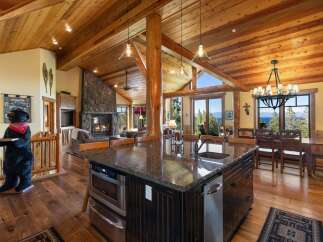 Experience luxury mountain living in this stunning home featuring a grand stone fireplace and vaulted wood-beamed ceilings.