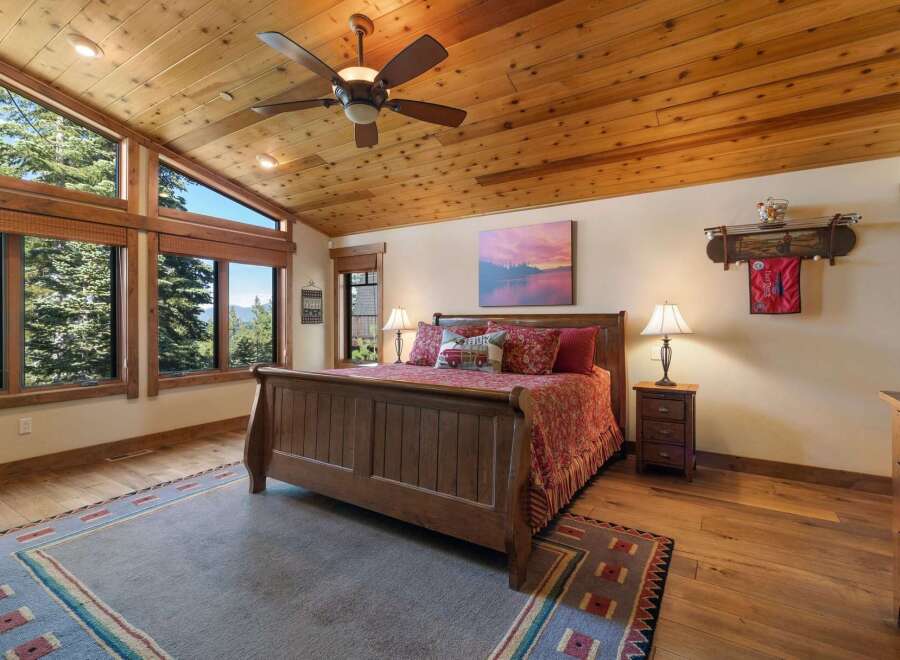 Experience breathtaking mountain views from this stunning bedroom, featuring a vaulted wood-paneled ceiling and expansive windows.