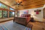 Experience breathtaking mountain views from this stunning bedroom, featuring a vaulted wood-paneled ceiling and expansive windows.