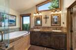 Indulge in luxury in this stunning bathroom featuring a deep soaking tub with a view of the serene lake and surrounding forest.