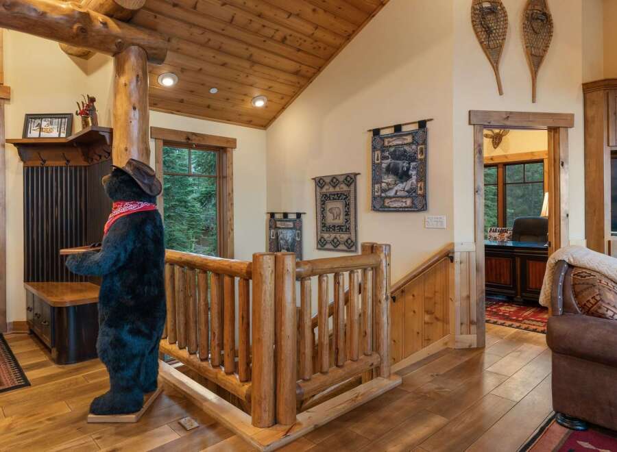 Experience rustic charm in this mountain lodge-inspired entryway, featuring a life-sized bear statue and a cozy log railing.