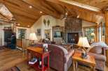 Experience rustic charm in this inviting living room, featuring a grand stone fireplace and a vaulted wood-paneled ceiling.