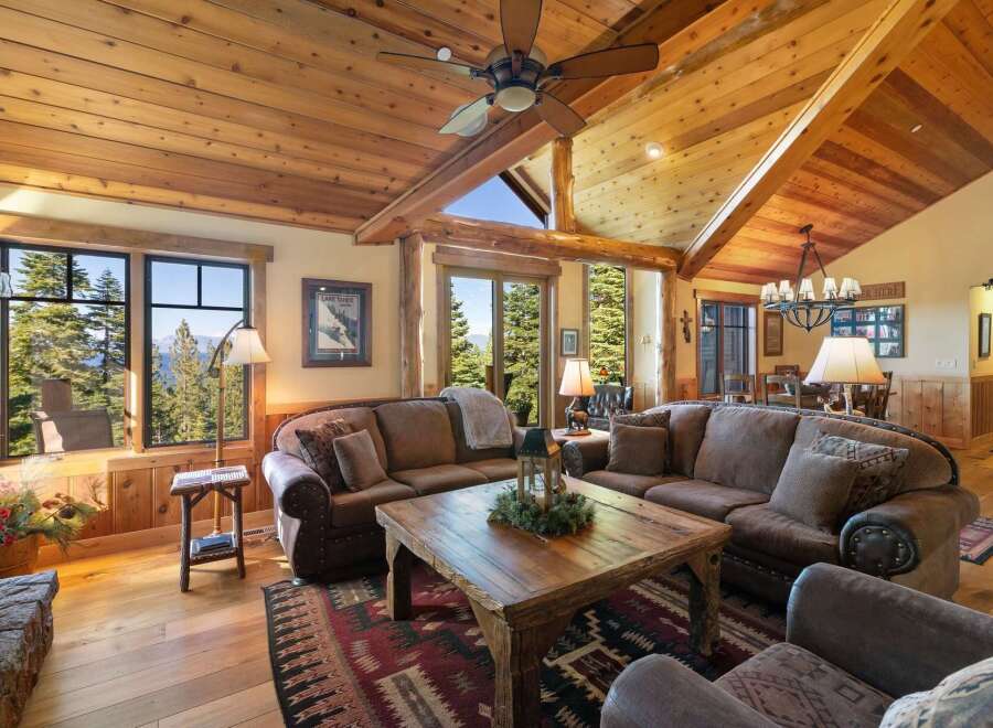 Experience rustic luxury in this stunning mountain lodge living room, featuring a grand stone fireplace and soaring vaulted ceilings with exposed wooden beams.