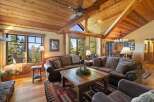 Experience rustic luxury in this stunning mountain lodge living room, featuring a grand stone fireplace and soaring vaulted ceilings with exposed wooden beams.