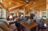 Experience rustic charm in this spacious living area, featuring a vaulted wood-paneled ceiling with exposed beams and a cozy stone fireplace.