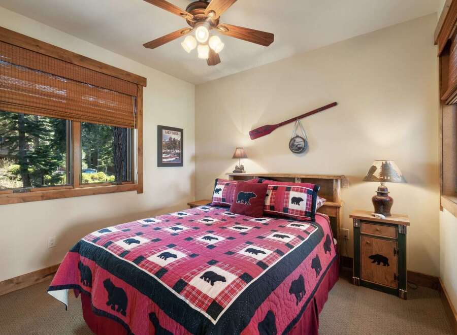 Experience rustic charm in this cozy bedroom, featuring a queen-sized bed adorned with a charming bear-themed quilt and matching pillows.