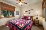 Experience rustic charm in this cozy bedroom, featuring a queen-sized bed adorned with a charming bear-themed quilt and matching pillows.