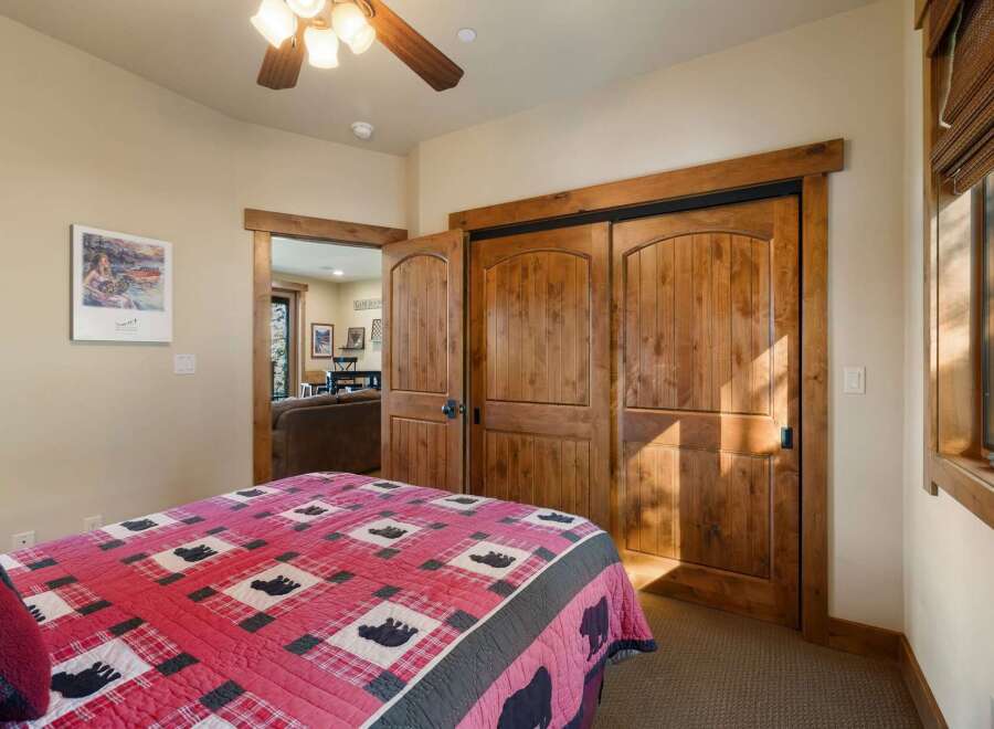 This charming bedroom features a cozy queen bed adorned with a rustic bear-themed quilt, perfect for a mountain retreat.