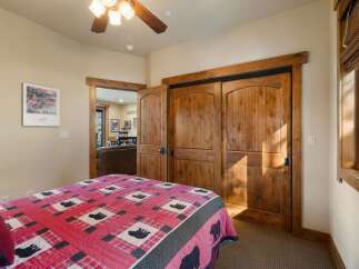This charming bedroom features a cozy queen bed adorned with a rustic bear-themed quilt, perfect for a mountain retreat.
