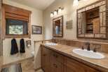 This rustic bathroom features a double vanity with warm wood cabinetry and tiled countertops, complemented by oil-rubbed bronze fixtures.