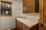 This laundry room features a large wooden vanity with a tiled countertop and a deep sink, perfect for household chores.