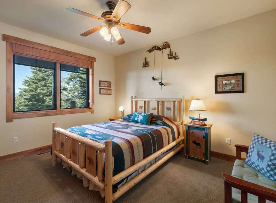 Experience rustic charm in this cozy bedroom, featuring a log-style bed adorned with a vibrant geometric blanket and a plush accent pillow.